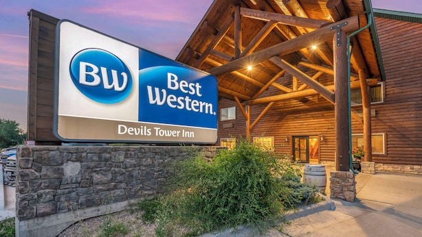 A Best Western sign in front of a wooden building with a stone base and a covered entrance.