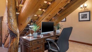 A wooden desk with a computer, a chair, and decorative plants.