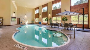 An indoor swimming pool with a 3ft 6in depth marker, surrounded by wooden walls, large windows, and a seating area with tables and chairs.