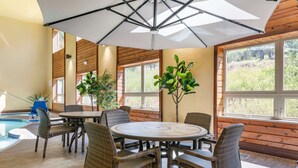 A poolside area with wicker furniture, a round table, and a ceiling fan.