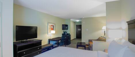 Habitación de hotel con una cama grande, un escritorio con silla, televisión y lámpara de escritorio.