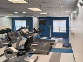 A gym with treadmills, a stationary bike, and a rowing machine.