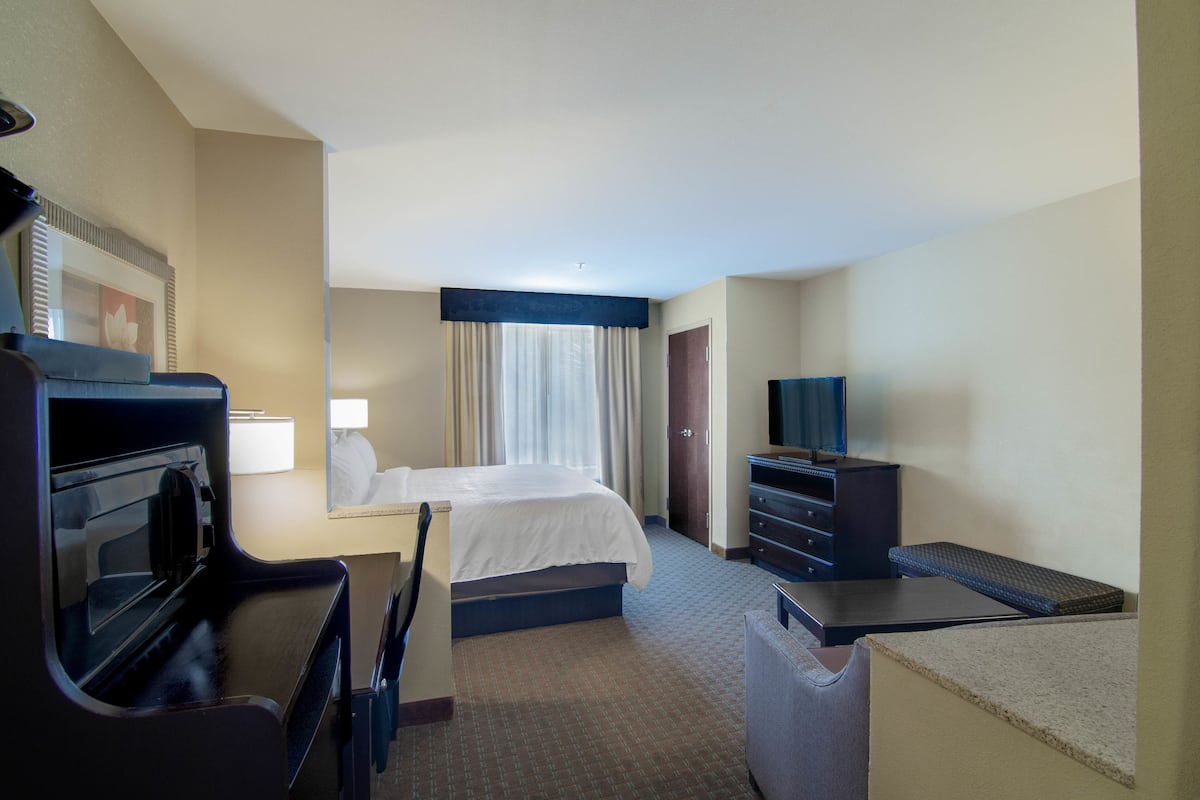 A hotel room with a bed, a desk with a computer, a television, and a microwave.