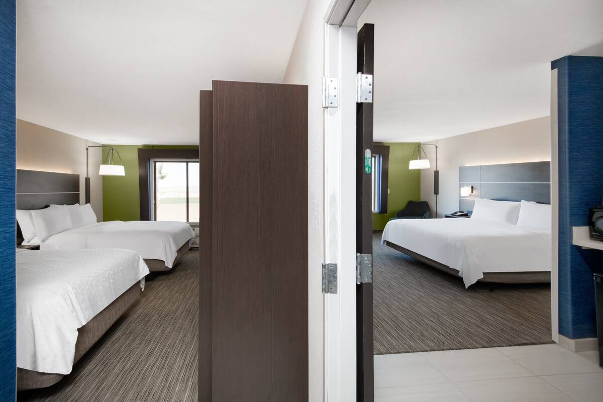 A hotel room with two beds, a desk, and a chair.