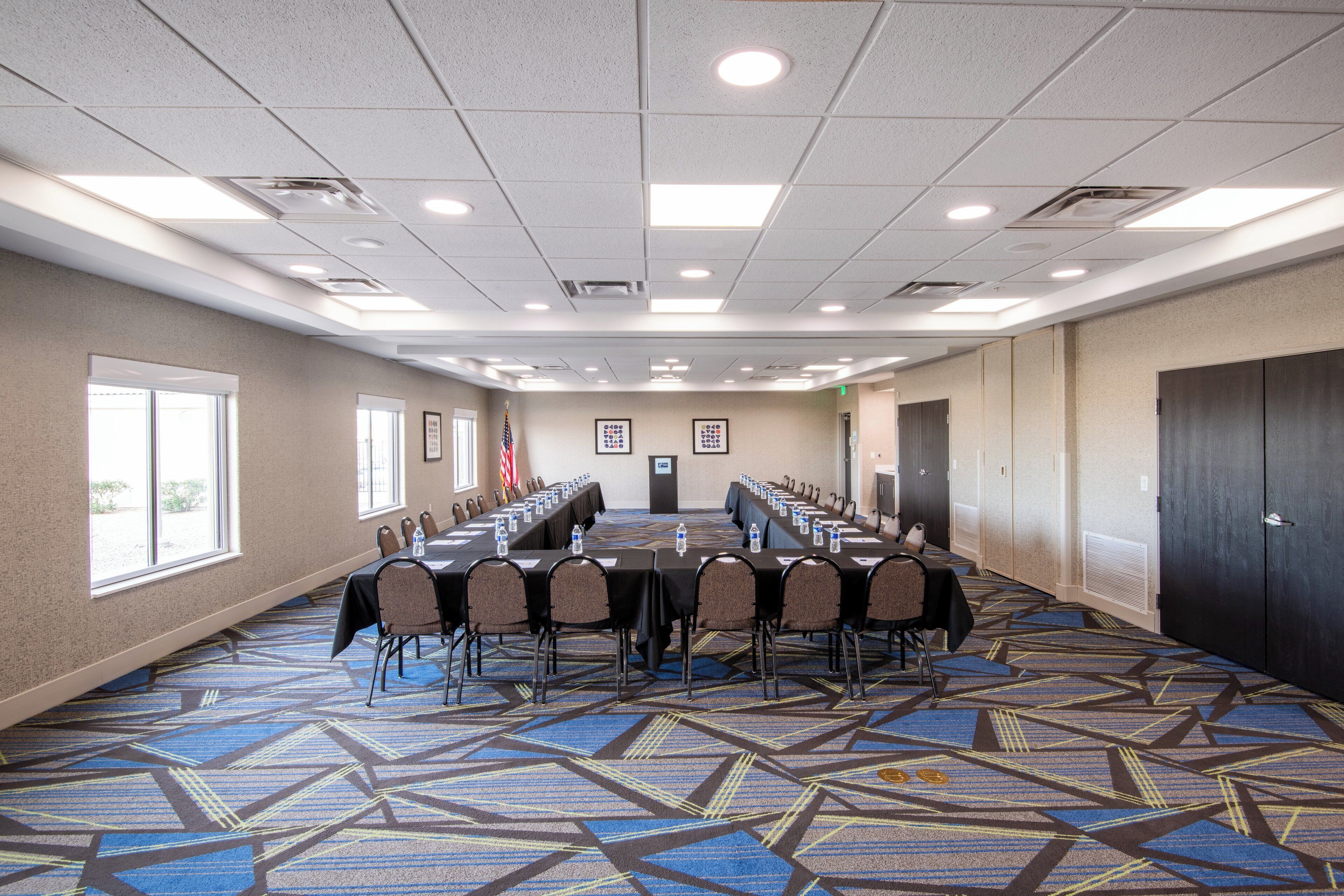 A conference room with a long table, chairs, and a carpeted floor.