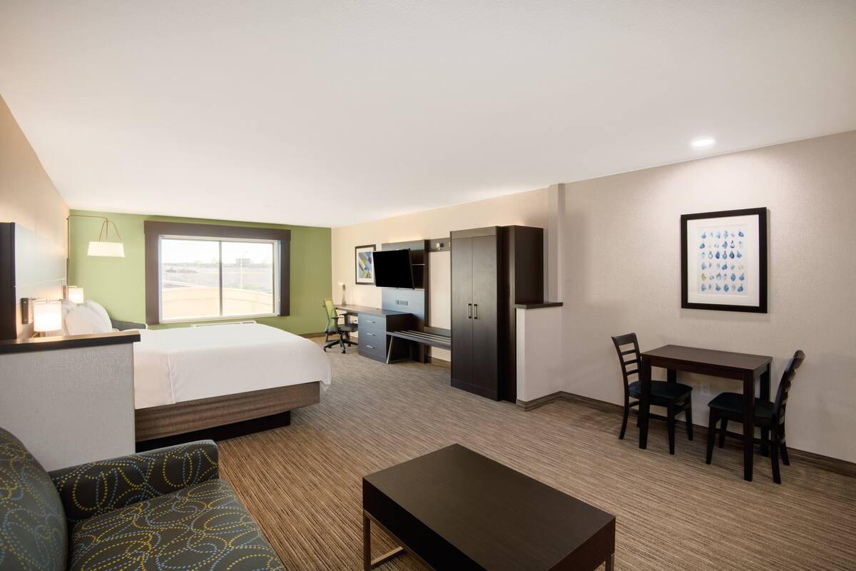A hotel room with a bed, a desk, a chair, a table, and a sofa.