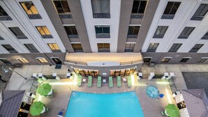 A rooftop pool area with lounge chairs and umbrellas, surrounded by a high-rise building with multiple windows. - Holiday Inn Express & Suites Yuma by IHG (Yuma)