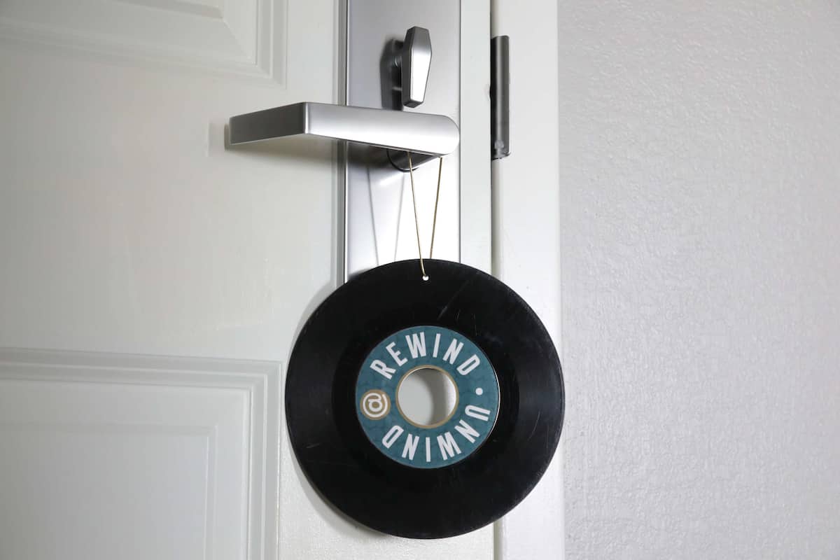 A black vinyl record hanging on a white door with a silver handle.