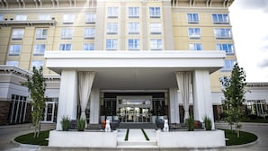 A hotel with a modern facade, large windows, and a central entrance with a canopy. - The Rewind West Des Moines, Tapestry Collection by Hilton (West Des Moines)