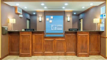 A reception desk with a Holiday Inn Express sign, a digital display, and a non-smoking property notice.