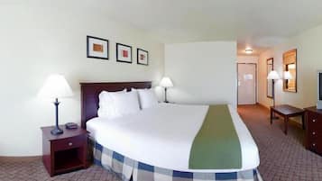 A hotel room with a large bed, two bedside tables with lamps, a small desk, and a television.