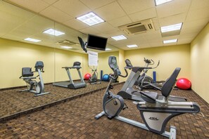 A fitness center with exercise equipment, a mirror, and a sign indicating the location. - Holiday Inn Express Hotel & Suites El Dorado, Kansas by IHG (El Dorado)