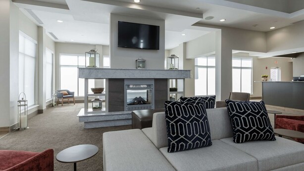 A modern living room with a fireplace, a flat-screen TV mounted above it, and a sofa with patterned cushions.
