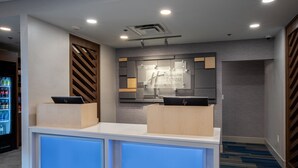 Een receptiebalie van een hotel met een modern design, inclusief een ontvangstruimte, een wandbord en een toonbank met een laptop.