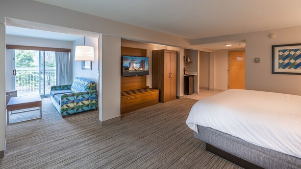 Een hotelkamer met een groot bed, een bank, een televisie en een houten kast.