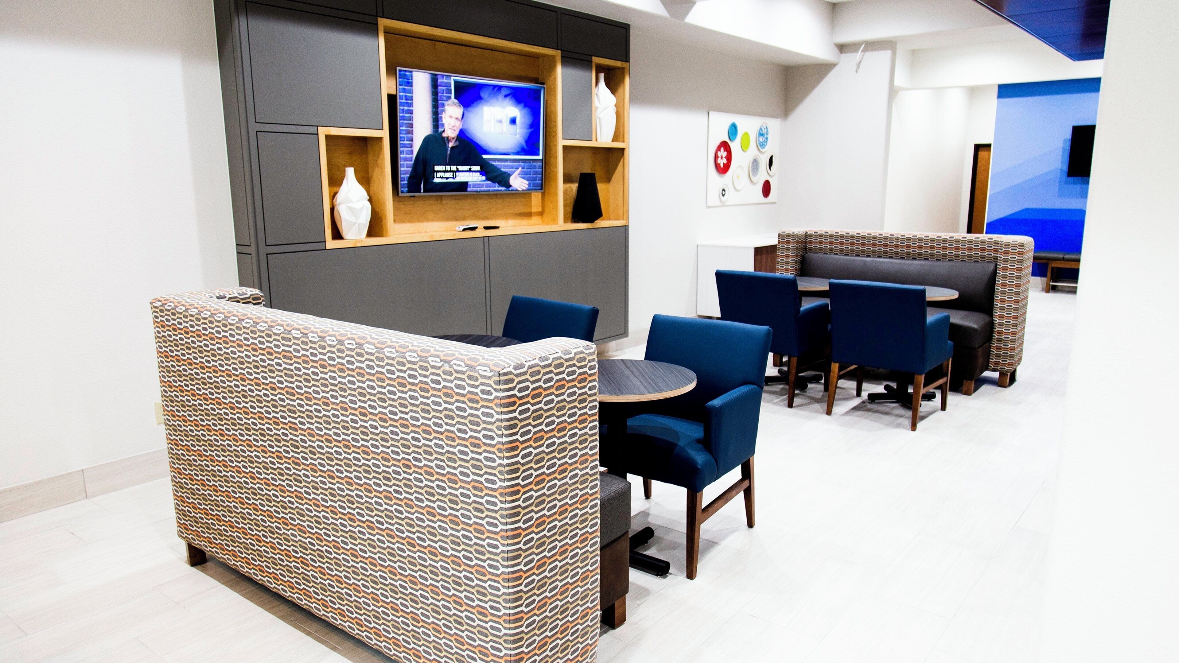 A modern lounge area with a television, seating, and decorative wall art.