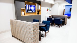 A modern lounge area with a television, seating, and decorative wall art.