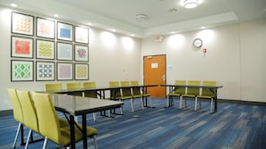 A conference room with a long table and chairs, a clock, and framed artwork on the wall.