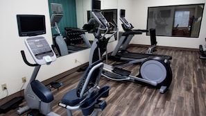 Une salle de sport équipée de divers appareils d’exercice, notamment des tapis de course et un appareil elliptique.