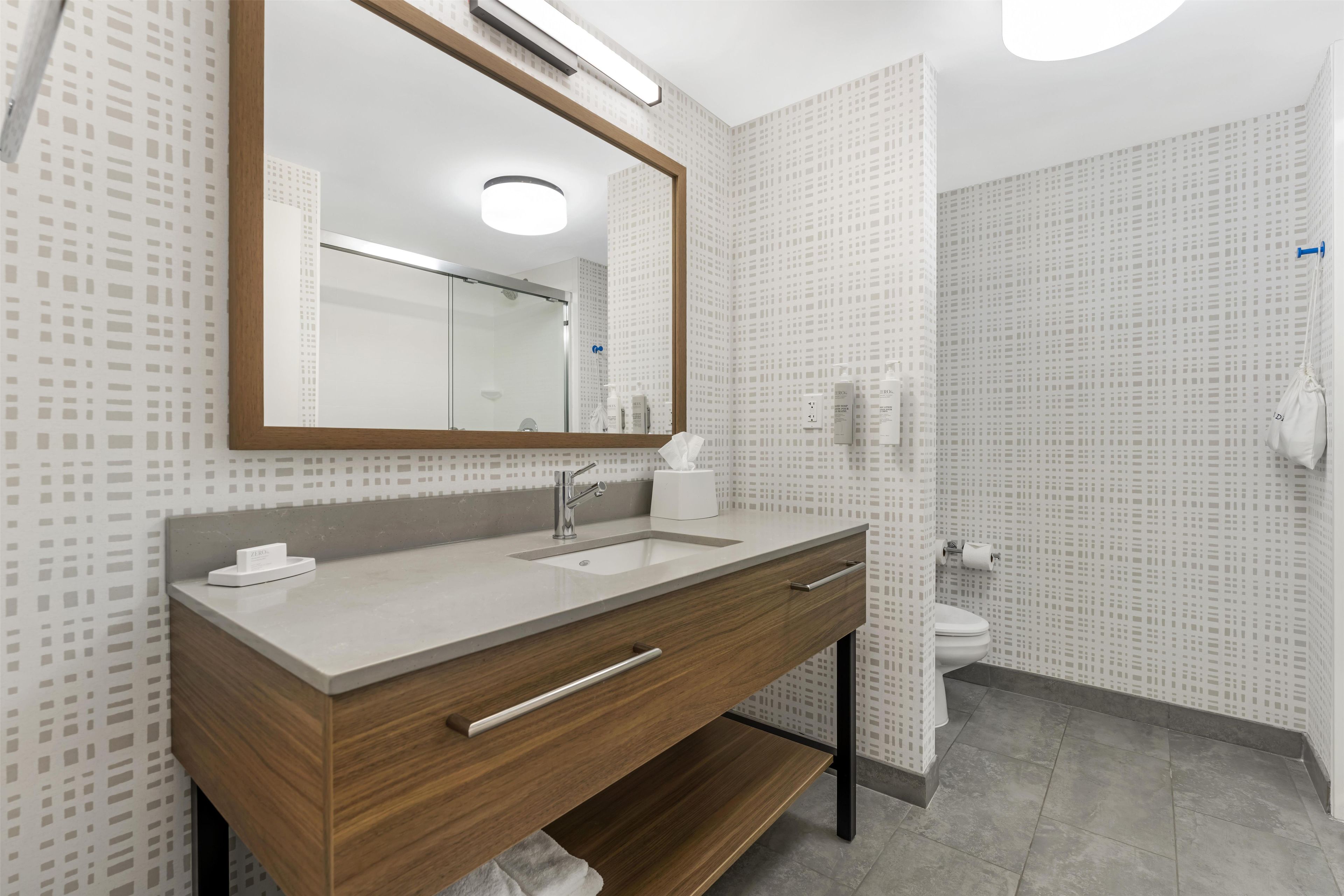 Une salle de bain moderne avec un meuble-lavabo en bois, un miroir, un évier et des toilettes.