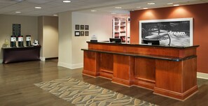 A hotel reception desk with a digital screen, a water dispenser, and a sign indicating the property is a Hilton Honors member. - Hampton Inn & Suites Pittsburgh-Meadow Lands (Washington)