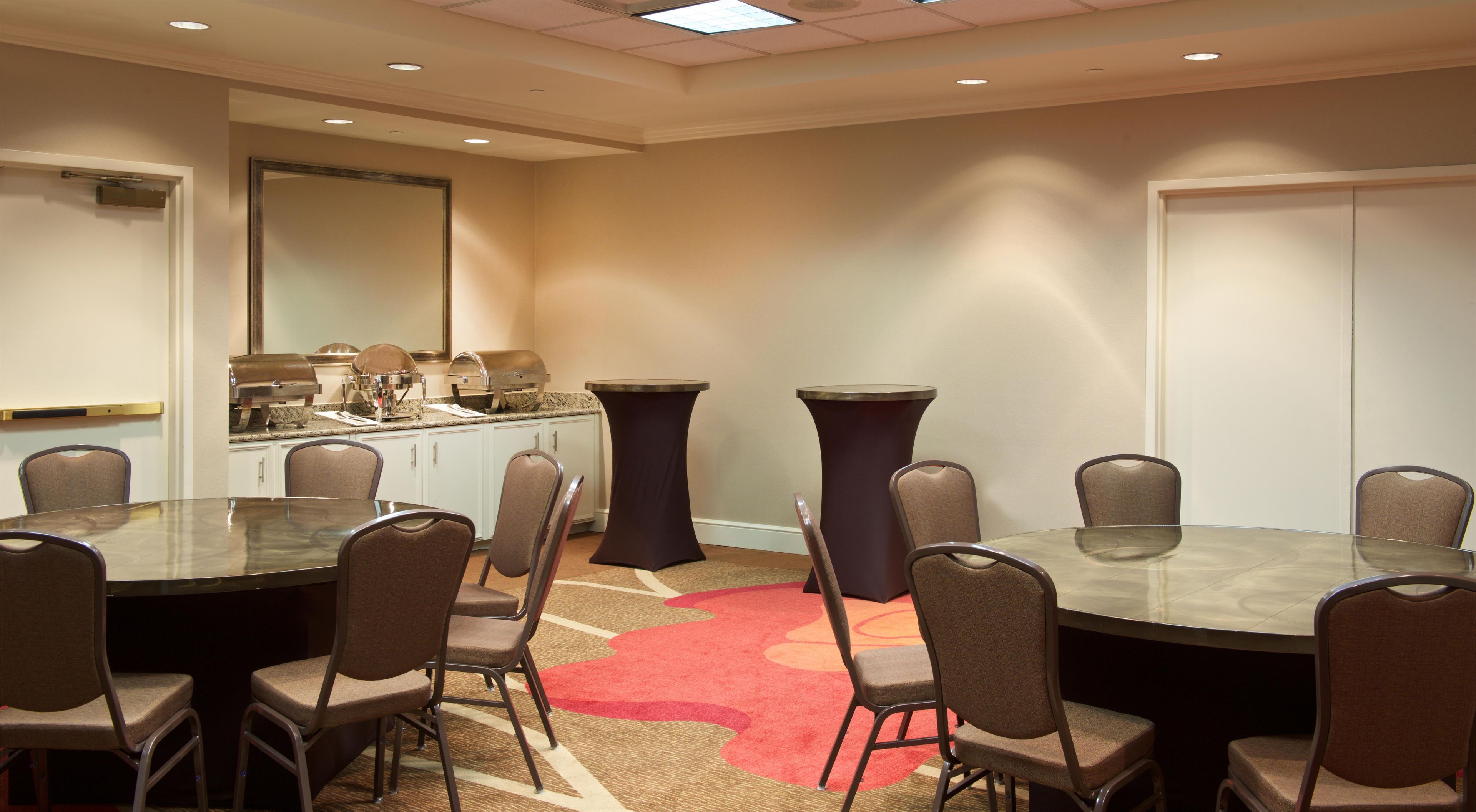 Une salle de conférence avec une table en verre, des chaises, un buffet et un tapis rouge.