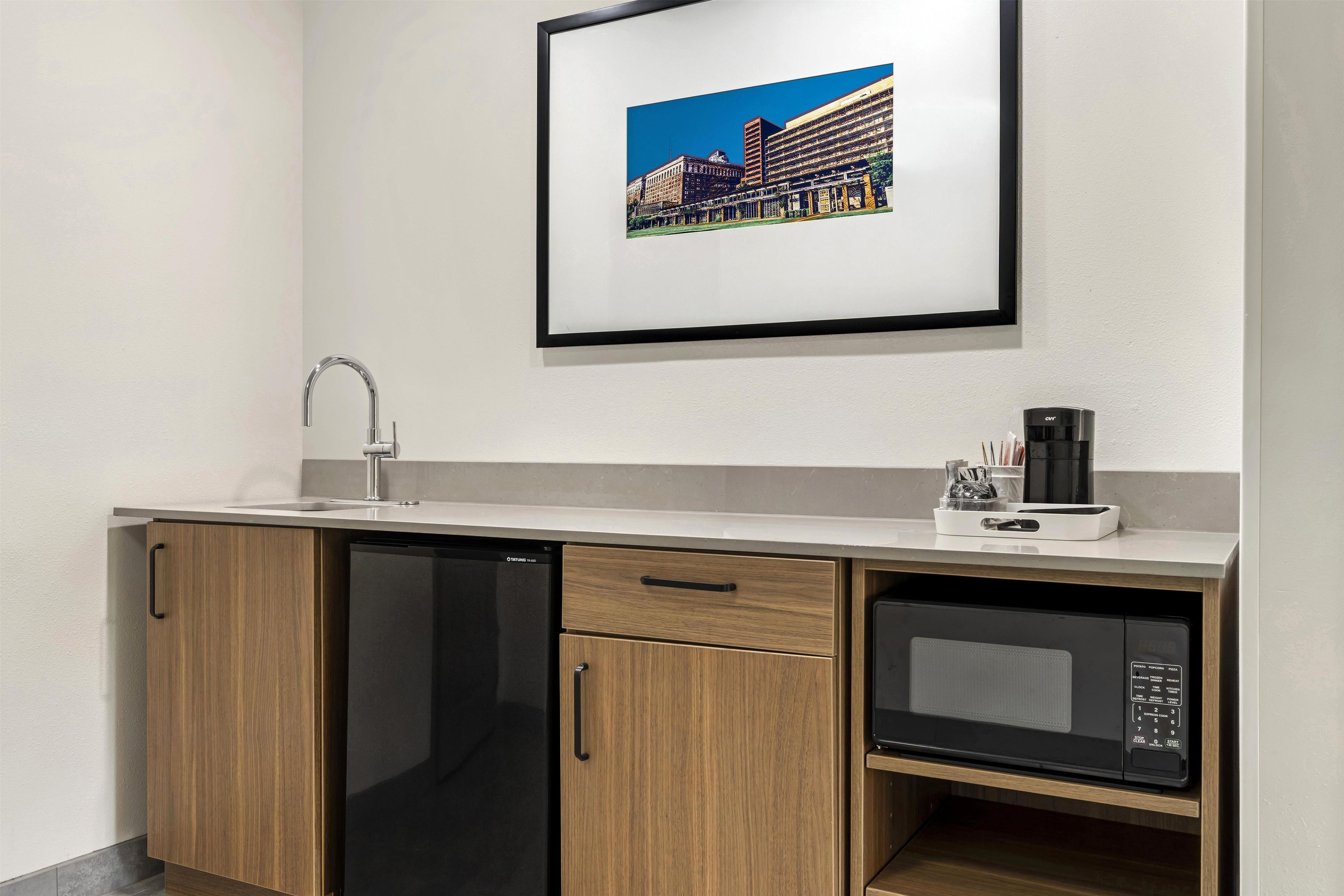 A compact kitchenette with a dishwasher, microwave, and a coffee maker.