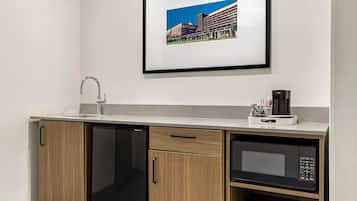 A compact kitchenette with a dishwasher, microwave, and a coffee maker.