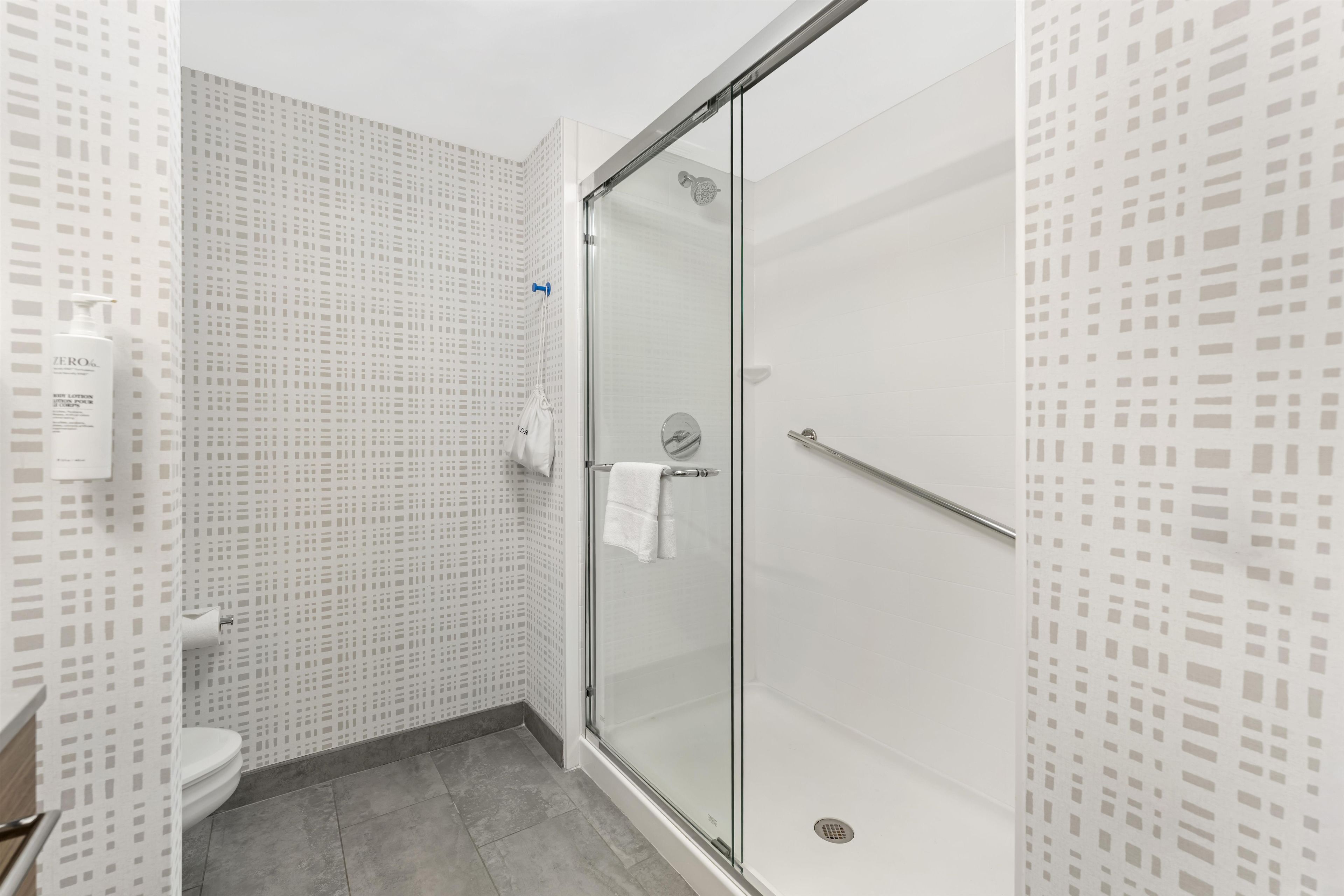 A modern bathroom with a glass shower enclosure, a toilet, and a patterned wall.