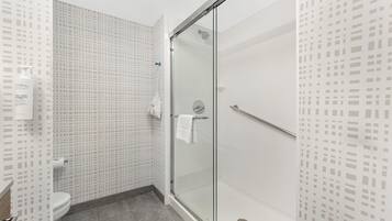 A modern bathroom with a glass shower enclosure, a toilet, and a patterned wall.
