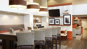 A modern dining area with a long table, multiple chairs, and pendant lighting.