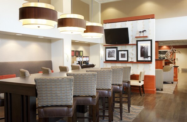 A modern dining area with a long table, multiple chairs, and pendant lighting.