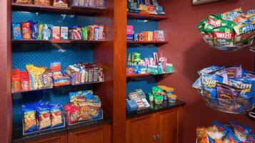A snack and beverage display in a store with various snacks, drinks, and toiletries.