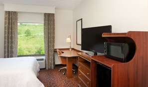 A hotel room with a bed, a desk with a chair, a television, a microwave, and a window with curtains. - Hampton Inn & Suites Pittsburgh-Meadow Lands (Washington)