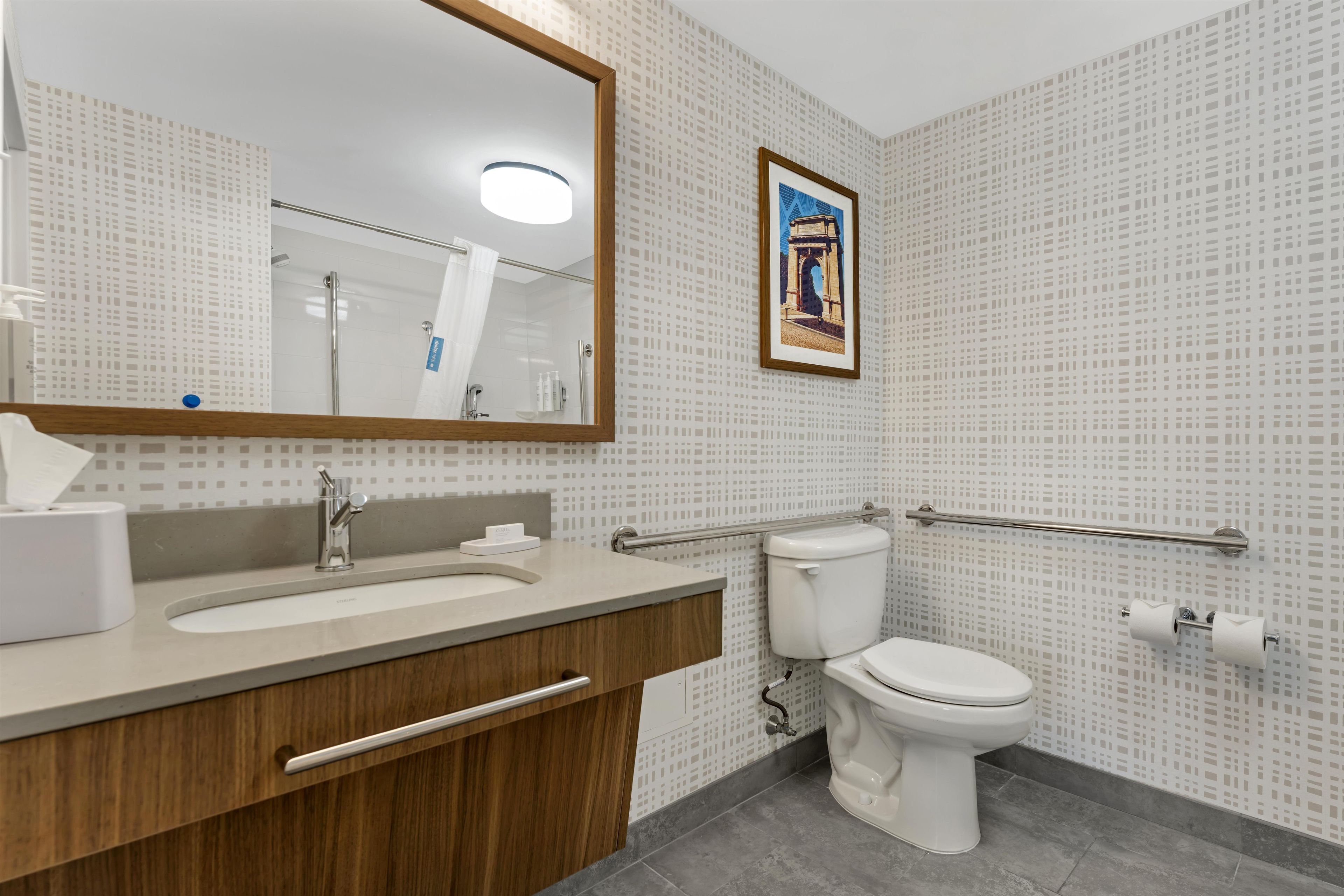 A modern bathroom with a large mirror, a sink, a toilet, and a shower.