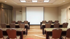 A conference room with a large projection screen, multiple tables, and chairs arranged for meetings. - Hampton Inn & Suites Pittsburgh-Meadow Lands (Washington)