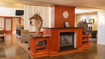 A lobby with a fireplace, wooden furniture, and a clock on the wall.