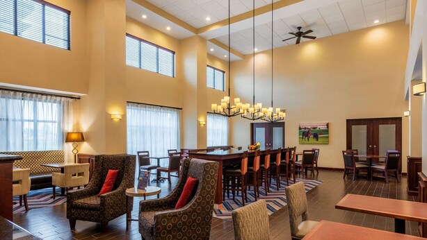 A spacious hotel lobby with high ceilings, large windows, and a central dining area with multiple tables and chairs. - Hampton Inn & Suites Hopkinsville (Hopkinsville)