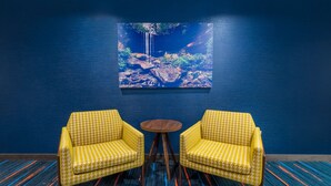 A room with two yellow patterned chairs, a small round wooden table, and a large painting of a waterfall on the wall. - Hampton Inn & Suites Hopkinsville (Hopkinsville)