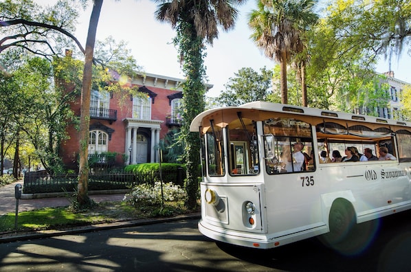 A vintage bus with the number 735, parked on a street with a red brick building and lush greenery in the background. - Holiday Inn Savannah Historic District by IHG (Savannah)