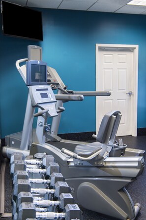A gym with exercise equipment, a television, and a door in the background. - Holiday Inn Savannah Historic District by IHG (Savannah)