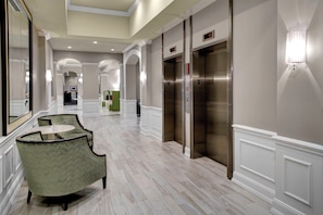 A hotel lobby with a marble floor, a reception desk, and two elevators. - Holiday Inn Savannah Historic District by IHG (Savannah)