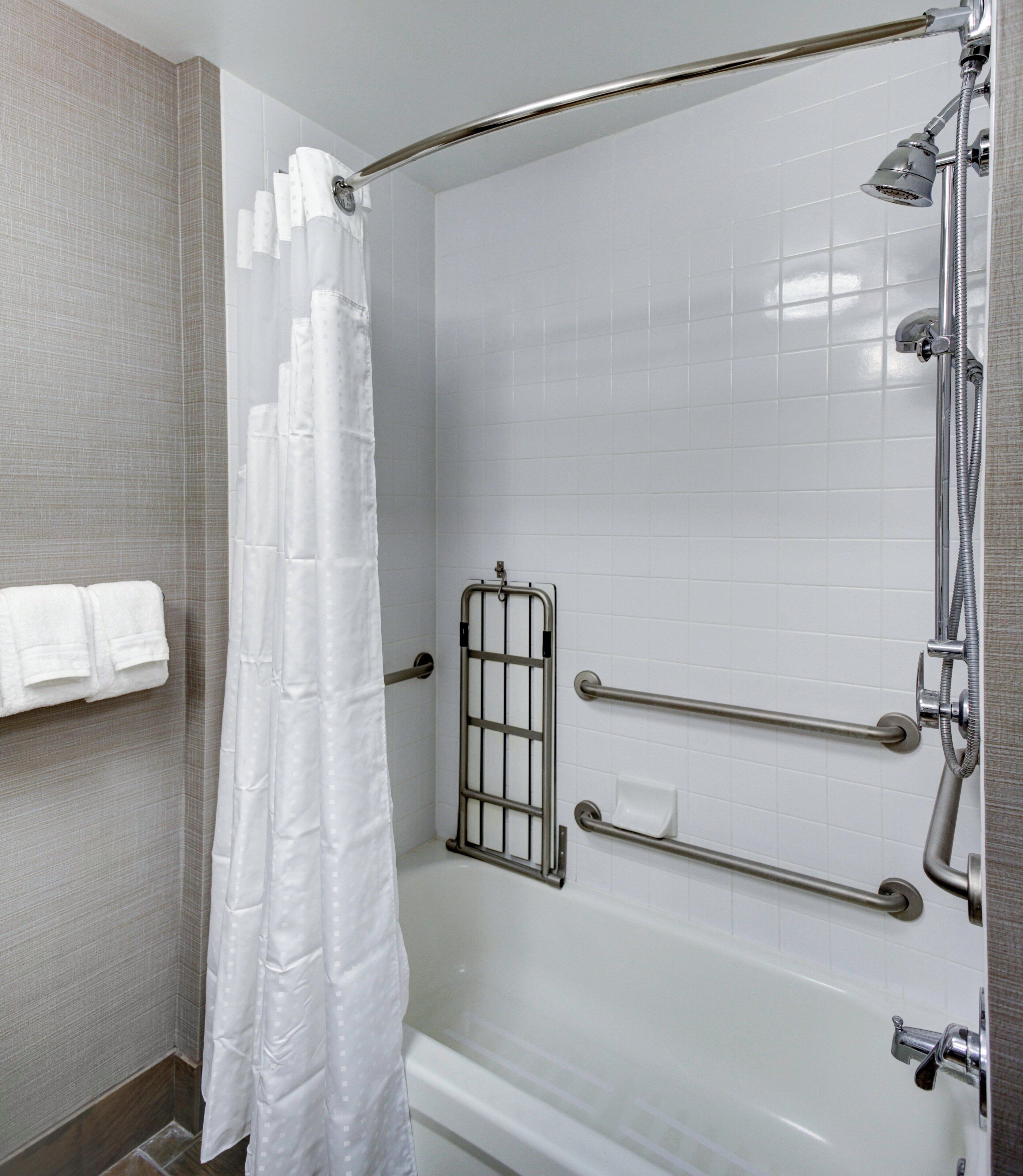 A shower area with a grab bar, a showerhead, and a curtain.