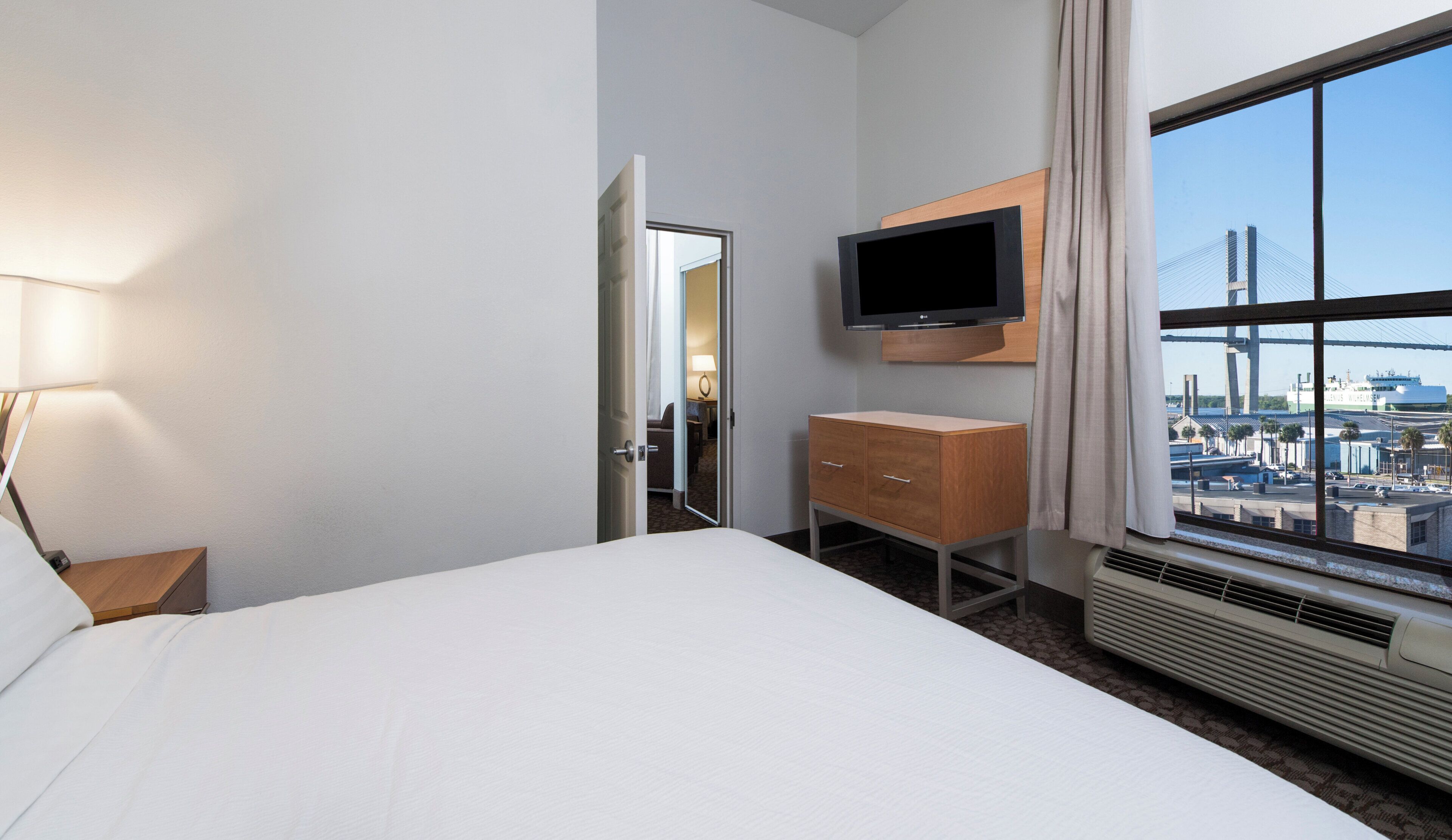Une chambre d’hôtel avec un lit, une télévision, une commode et une fenêtre donnant sur la ville.
