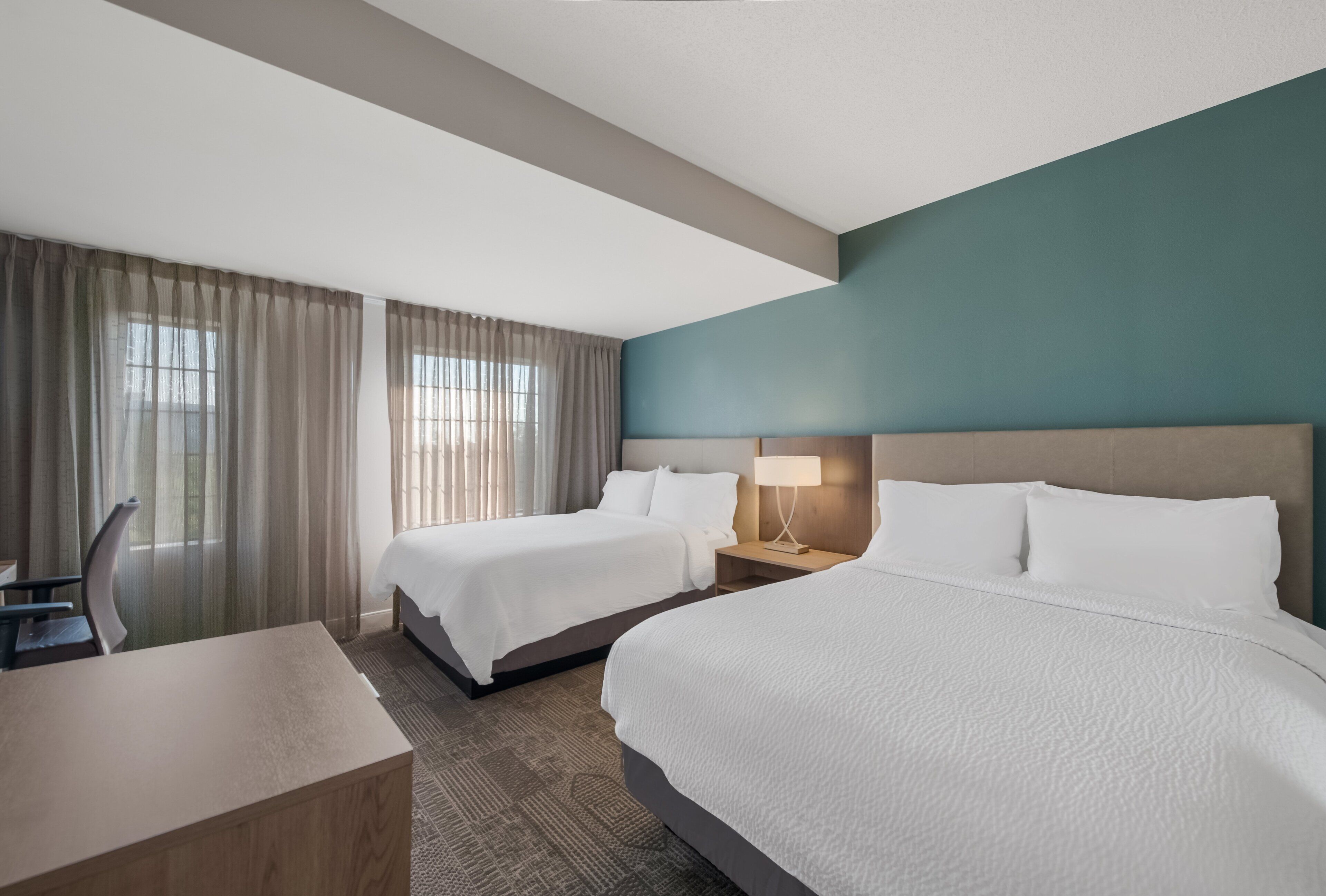 Una habitación de hotel con dos camas, un escritorio y una silla.