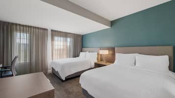 Una habitación de hotel con dos camas, un escritorio y una silla.