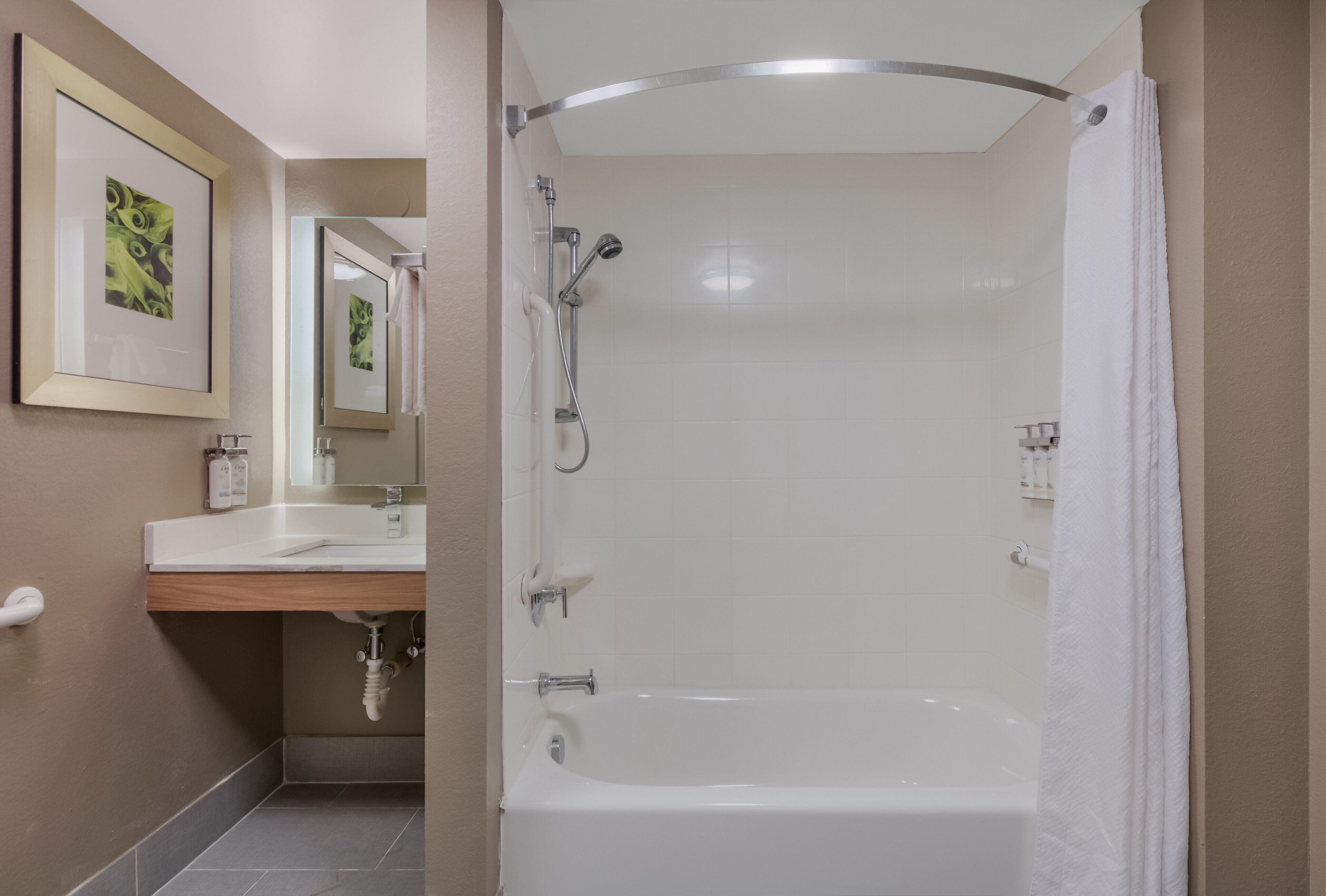 A modern bathroom with a white bathtub, a shower, and a vanity with a mirror.