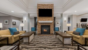 A spacious living room with a fireplace, sofas, and a flat-screen TV mounted above the fireplace. - Staybridge Suites Chesapeake by IHG (Chesapeake)