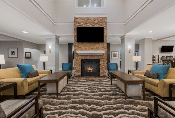 A spacious living room with a fireplace, sofas, and a flat-screen TV mounted above the fireplace. - Staybridge Suites Chesapeake by IHG (Chesapeake)