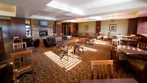 A spacious dining area with multiple tables and chairs, a fireplace, and a television mounted on the wall. - Holiday Inn Express Hotel & Suites Drayton Valley by IHG (Drayton Valley)